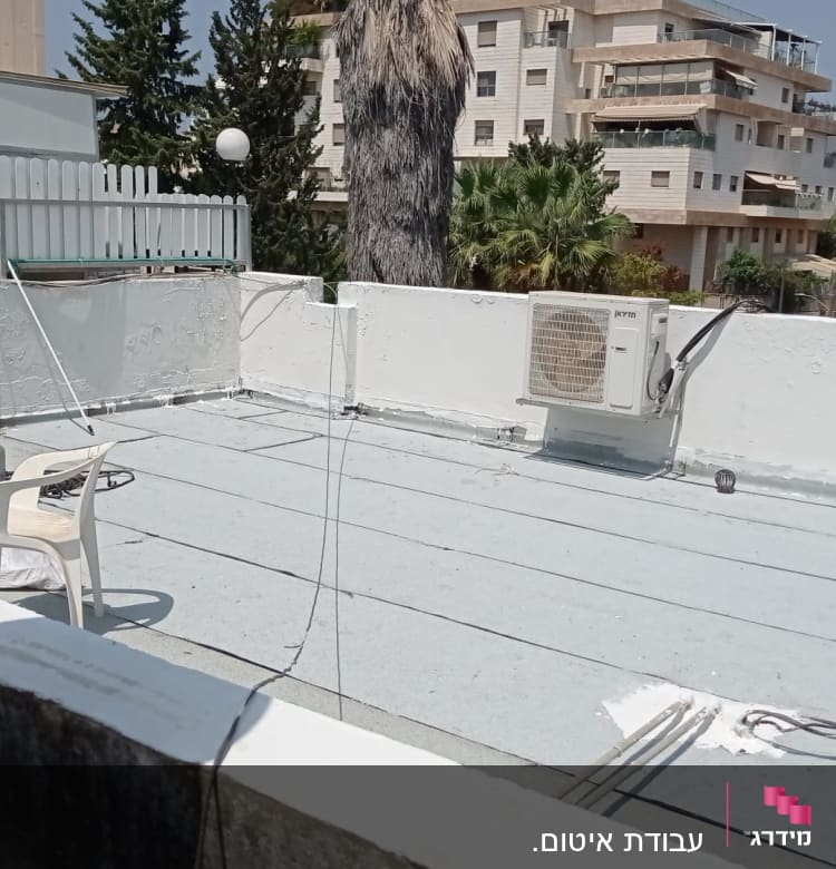 גג עם יריעות איטום, כיסא פלסטיק ומיכל גז